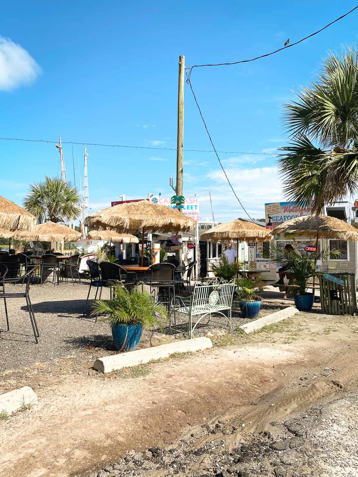 An outdoor beachy restaurant with palm trees on a sunny day