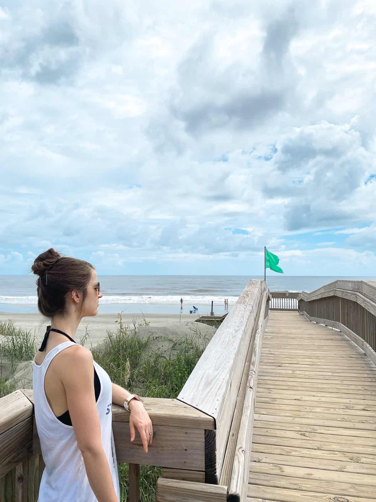 A woman with brown hair overlooking a boardwalk on a sunny beach in North Carolina