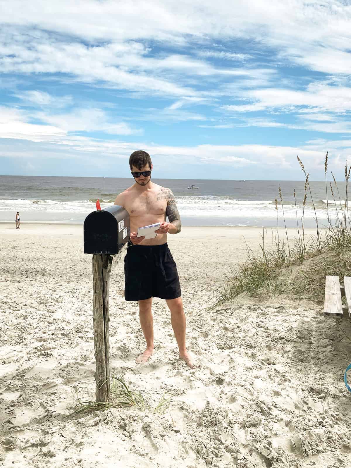 a man standing in a bathing suit on Sunset Beach NC at the Kindred Spirit Mailbox