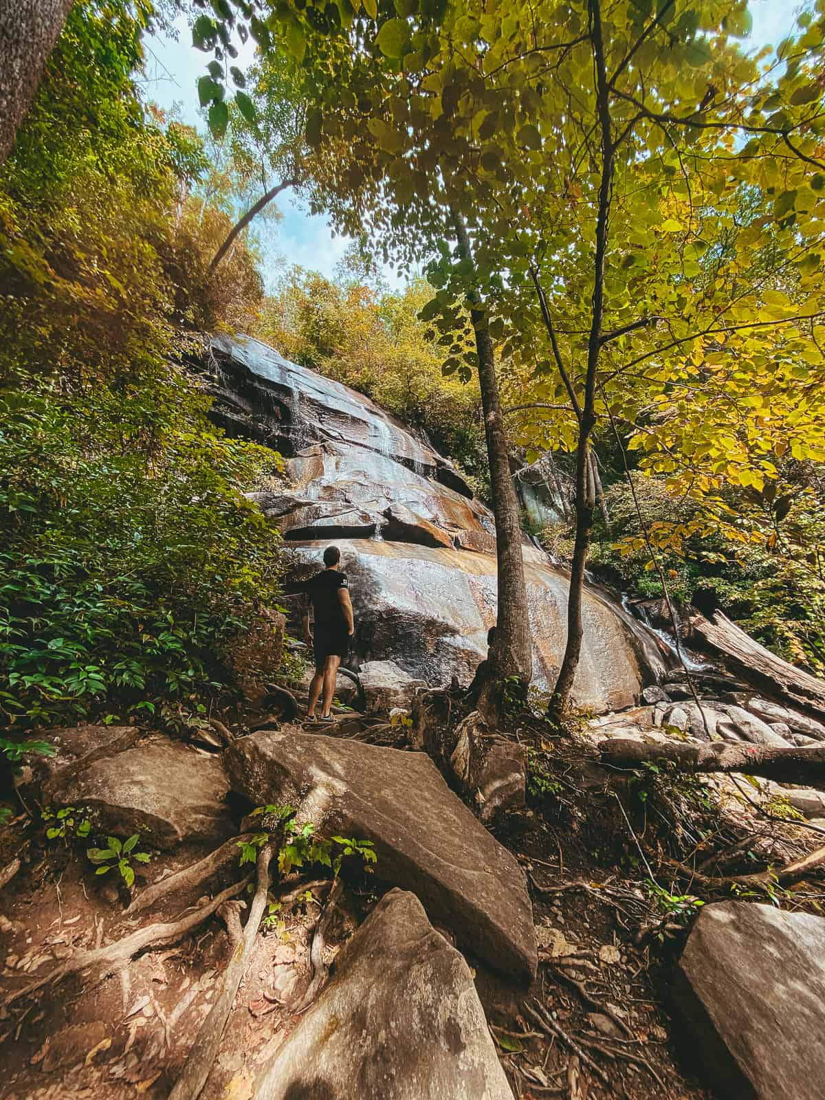 A man standing on rocks looking at Daniel Ridge Falls in Pisgah National Forest in North Carolina