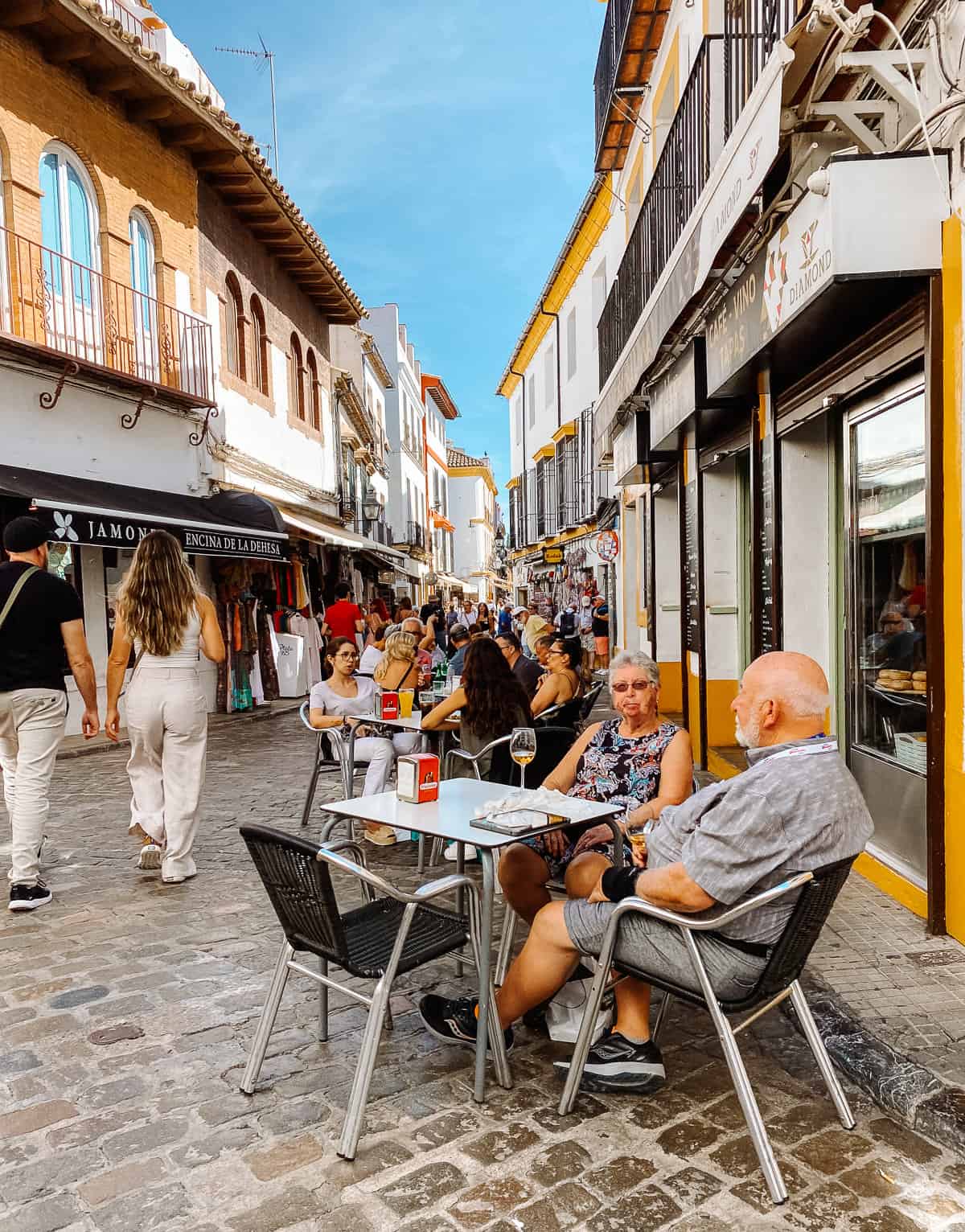 people sitting on a cobblestone street eating lunch
