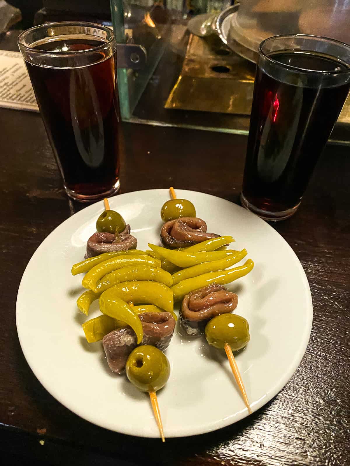 two skewers on a table with olives and anchovies