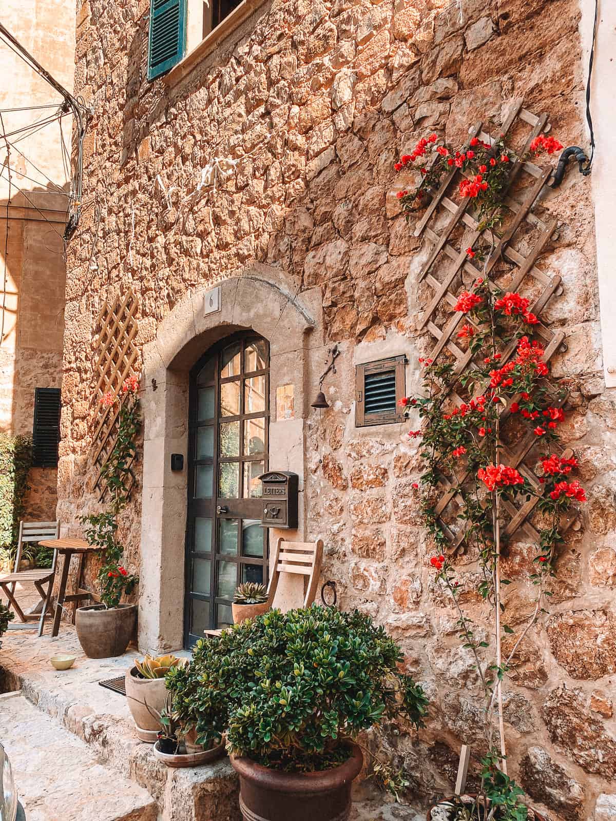 A beautiful stone building with a wooden door and pink flowers
