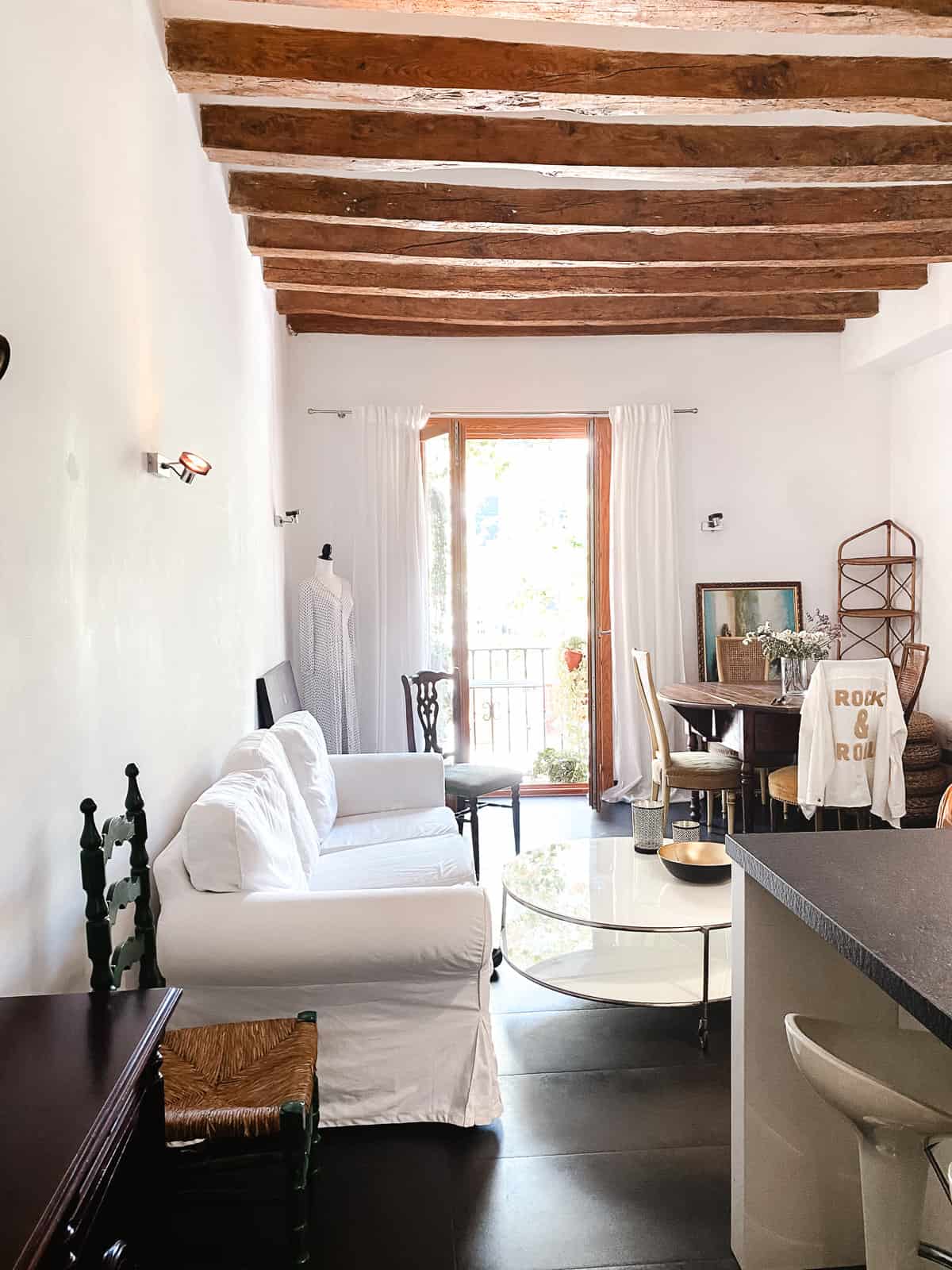 A white and wood apartment room with a big open door to a balcony