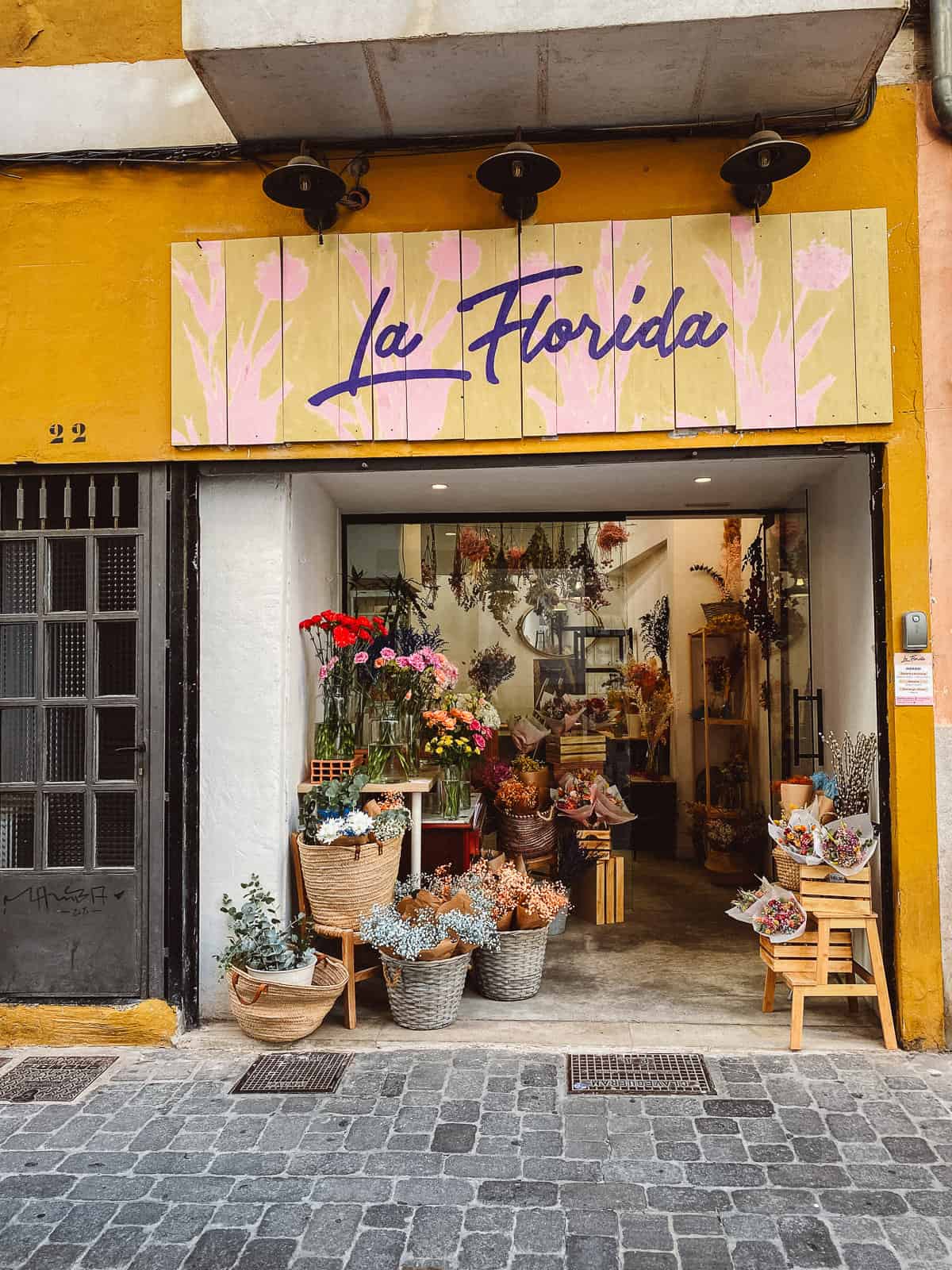 A yellow flower shop with a big open door and lots of flowers inside