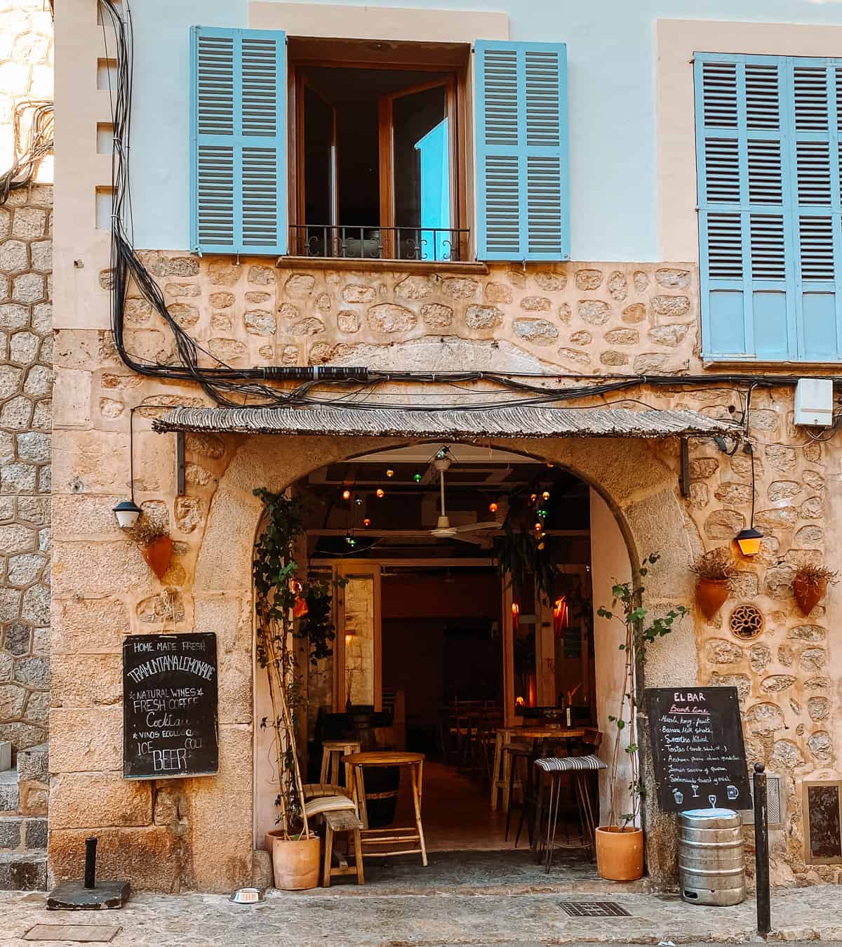 a cute stone wine bar with hanging lights and table and chairs in Mallorca