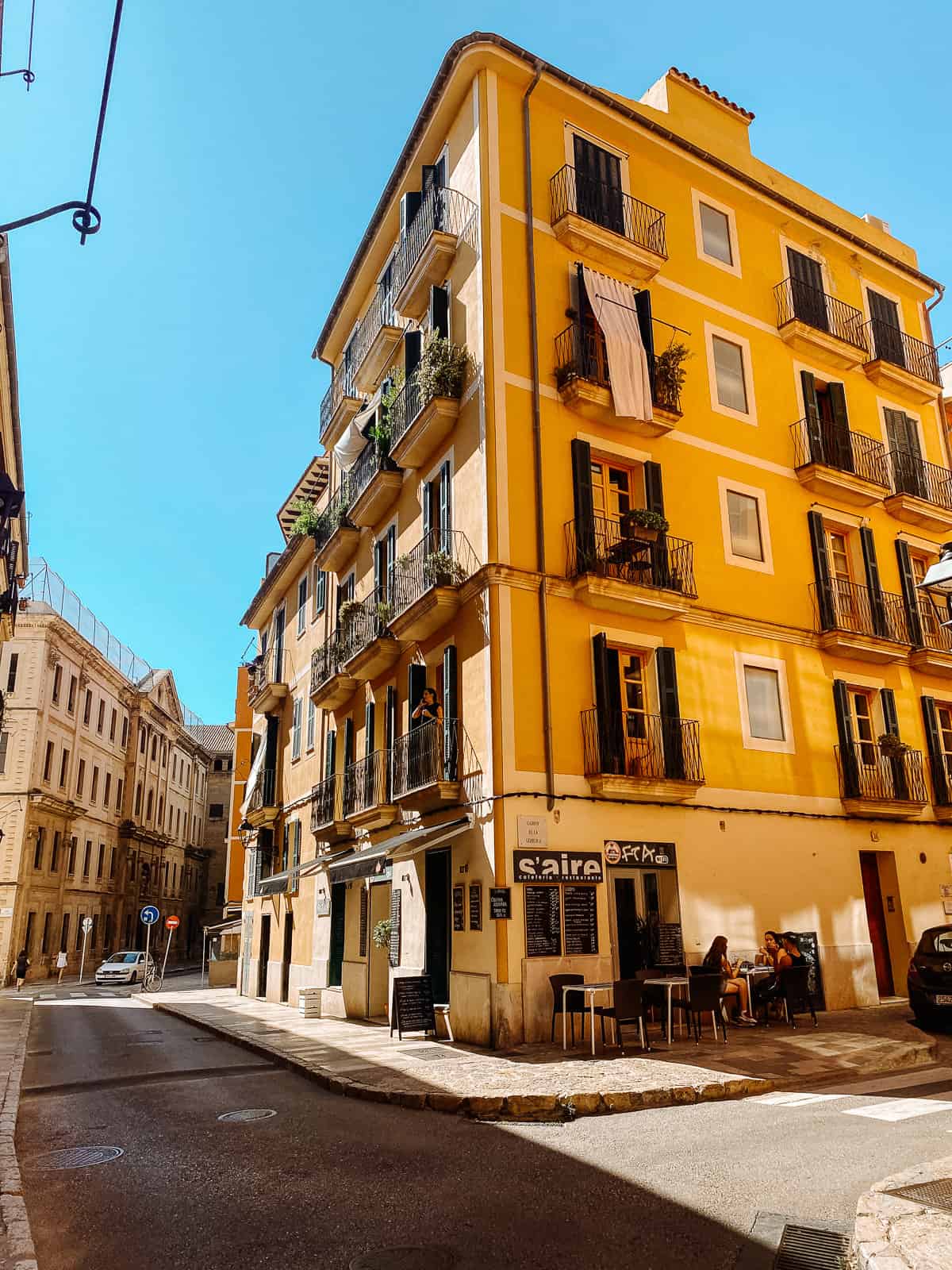 A yellow building on a road with one car driving down it in Mallorca Spain