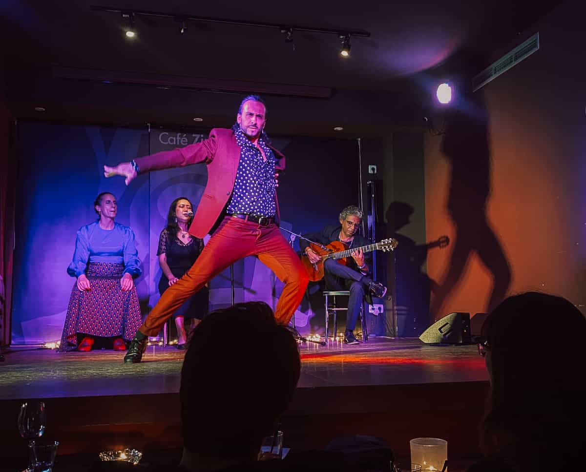 A man dancing flamenco in a red outfit on a stage.