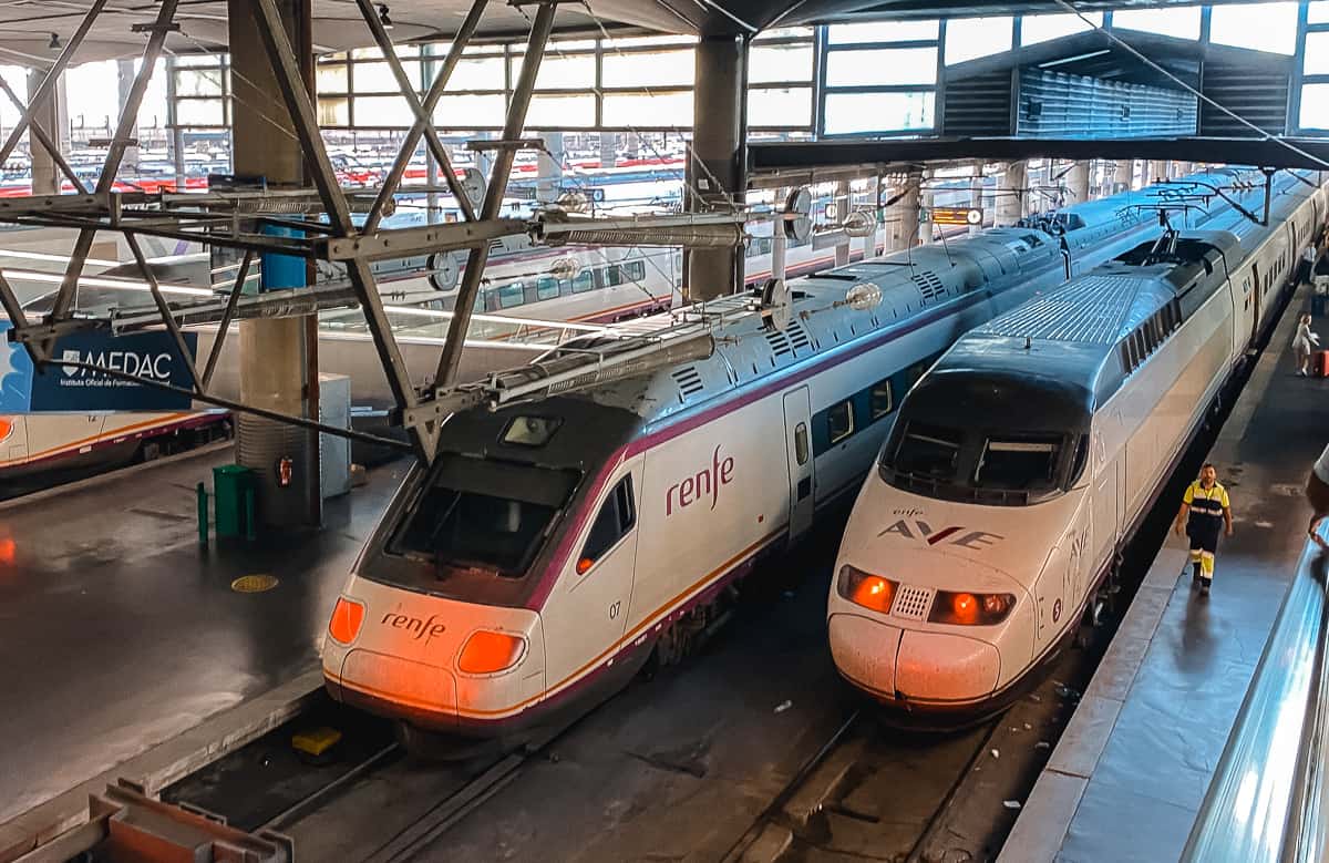 two trains sitting side by side in Madrid Atocha train station