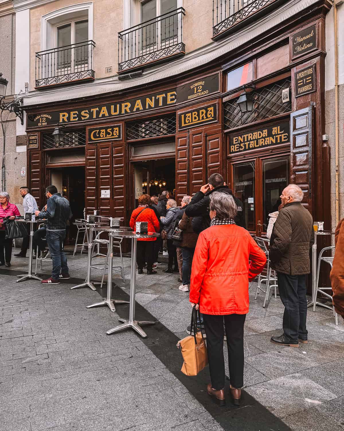 Busy street scene in front of Casa Labra Restaurant with people queueing outside, showcasing the popular and historic dining destination