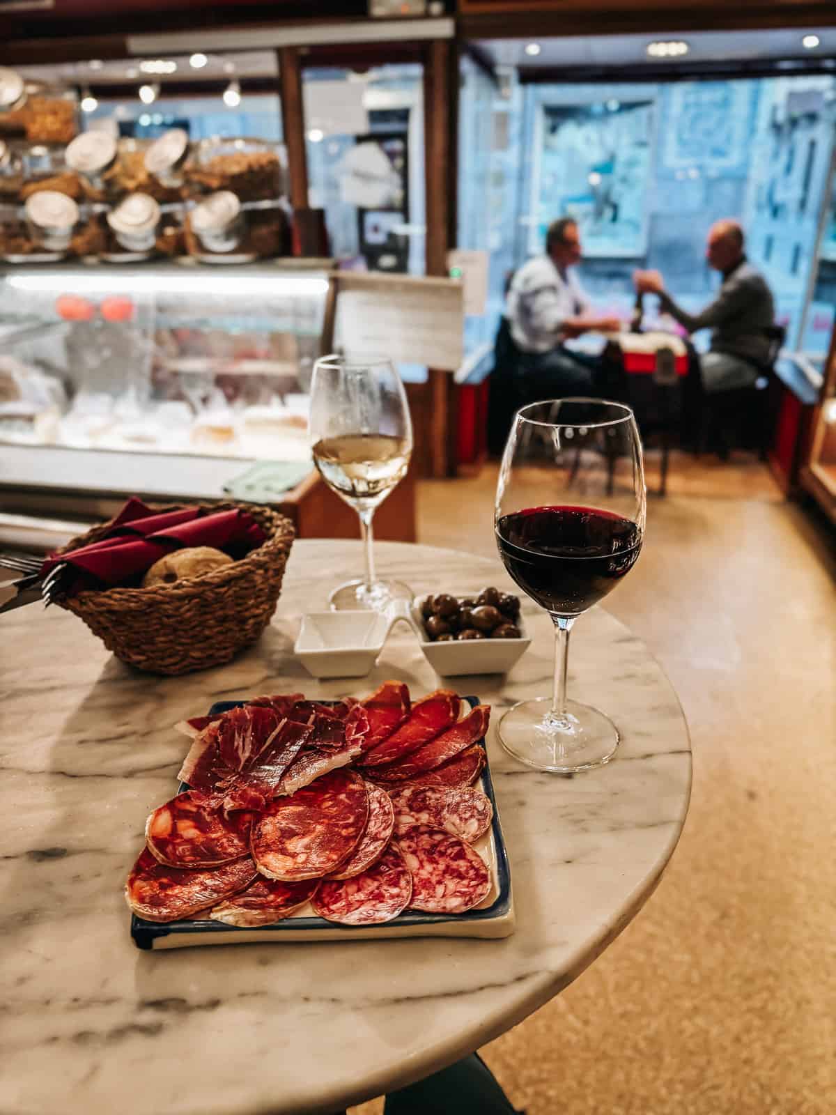 A charcuterie plate and 2 glasses of wine sit on a table