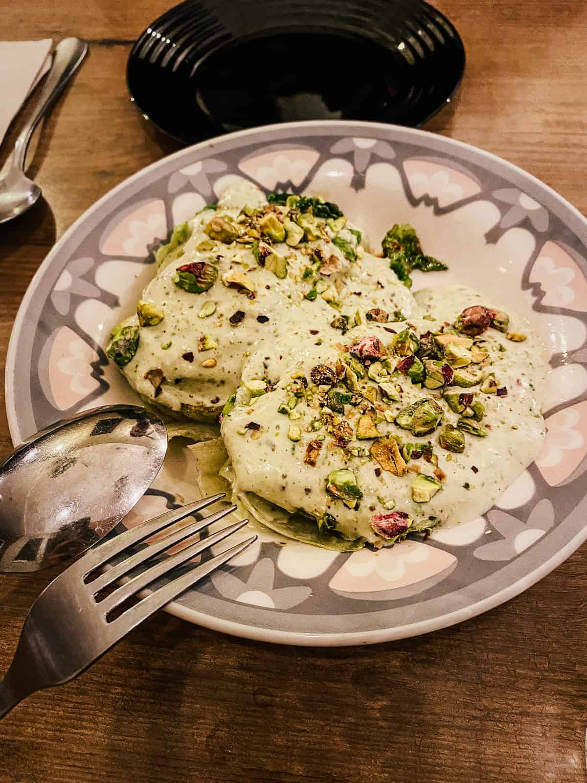 A plate of grilled lettuce garnished with green pistachios, served on a patterned plate, representing a refined and delicious tapa.
