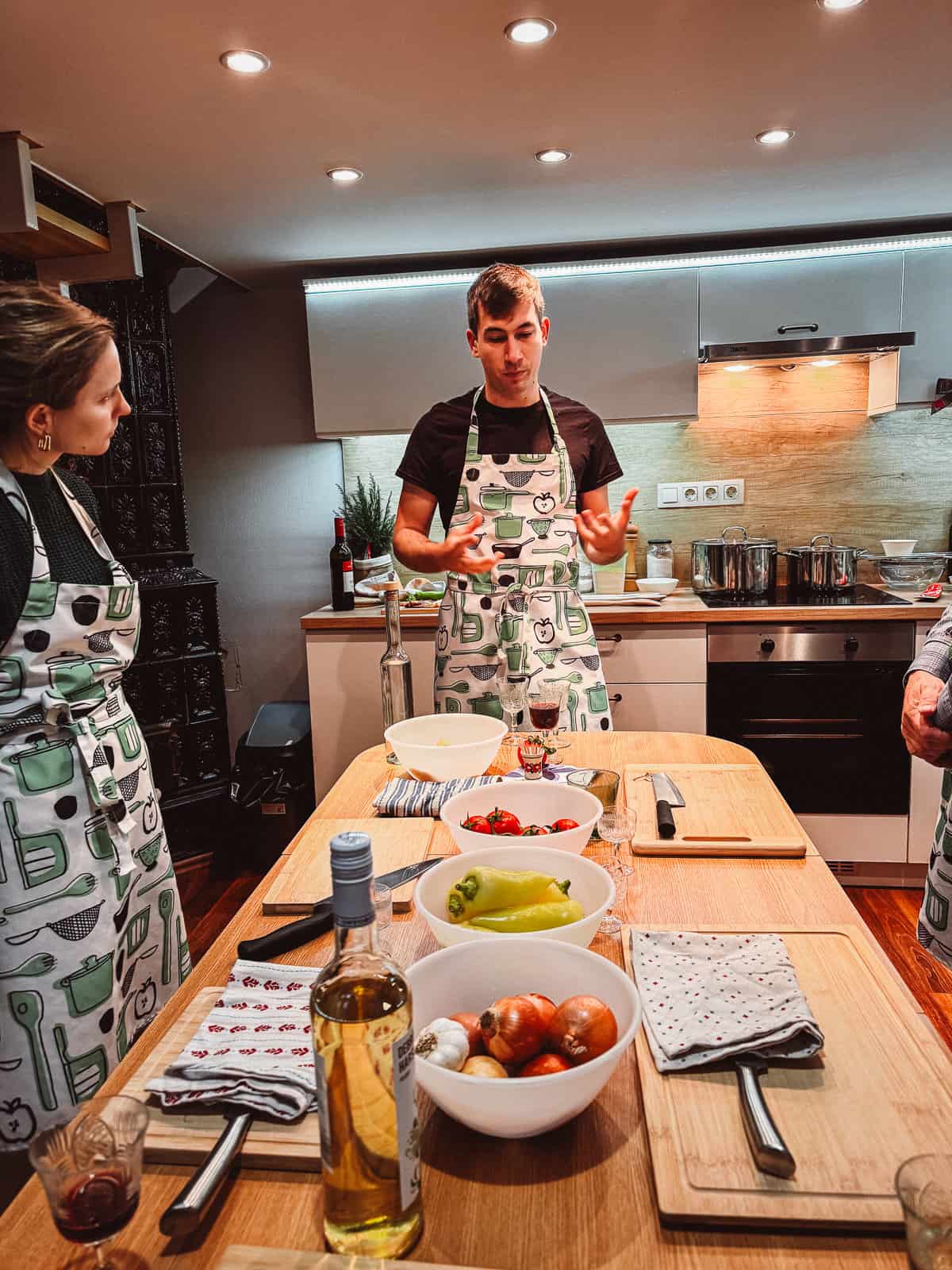 a man teaching a group how to cook on a long wooden table with tomatoes and a knife