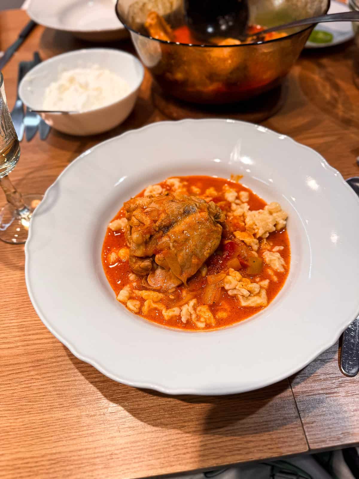 a large bowl of dumplings with creamy chicken paprika in a bright orange sauce