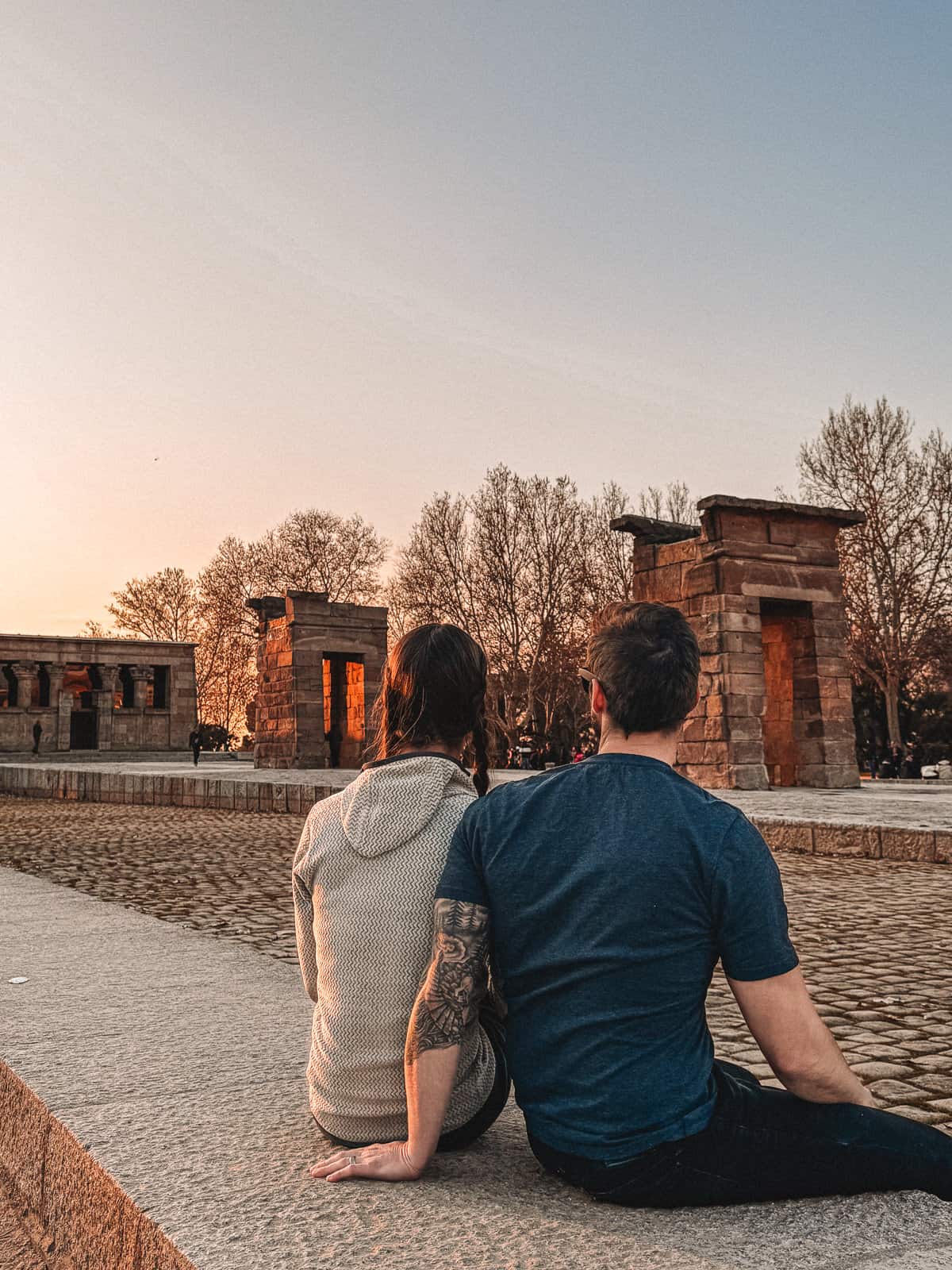A couple sitting peacefully at dusk by the Templo de Debod, an ancient Egyptian temple in the heart of Madrid.