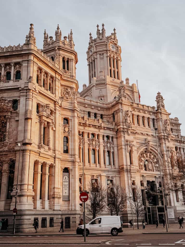 The intricate details of Cibeles Palace in Madrid, captured in golden hour light that accentuates the ornate architecture and grandeur of the city's iconic landmark.