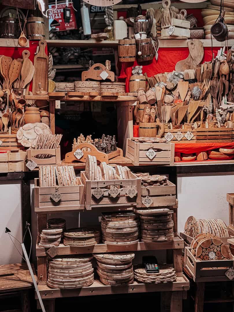 Wooden handicrafts market stall in Copenhagen displaying an assortment of kitchen utensils, cutting boards, and chess sets, with price tags visible.