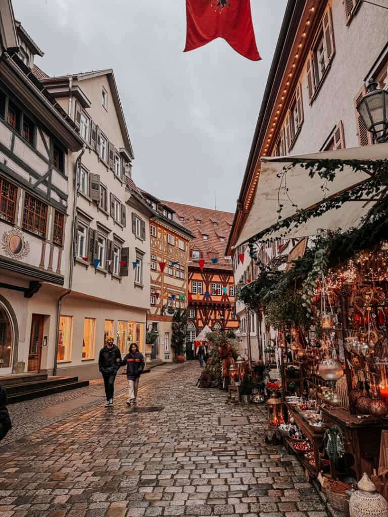 Cobbled streets lined with traditional half-timbered houses and festive Christmas market stalls in Esslingen am Neckar, Germany.