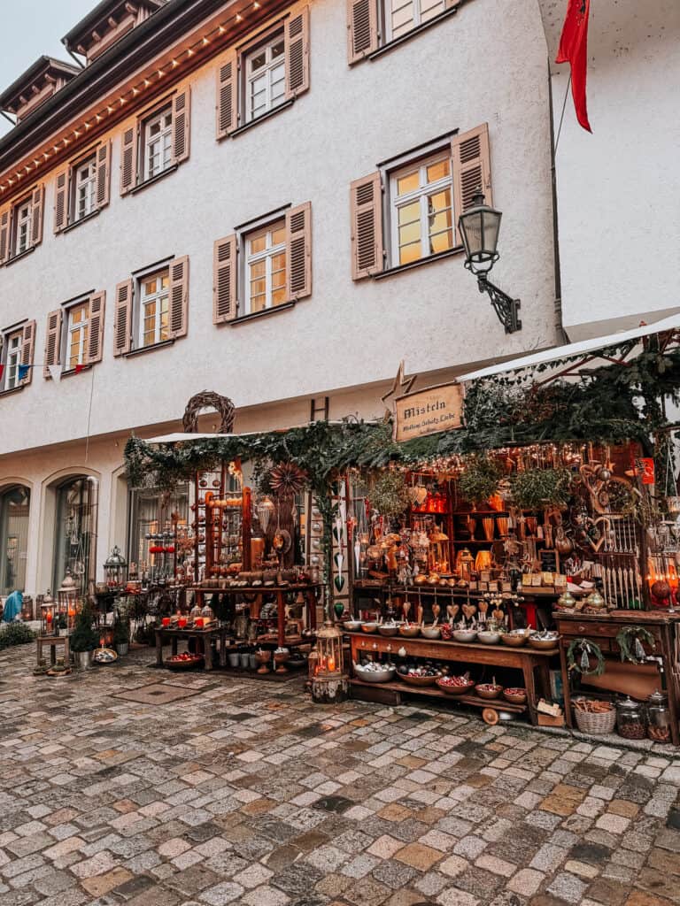 A picturesque street in Colmar, showcasing a variety of artisanal pottery and decorative items displayed outside a traditional Alsatian shop