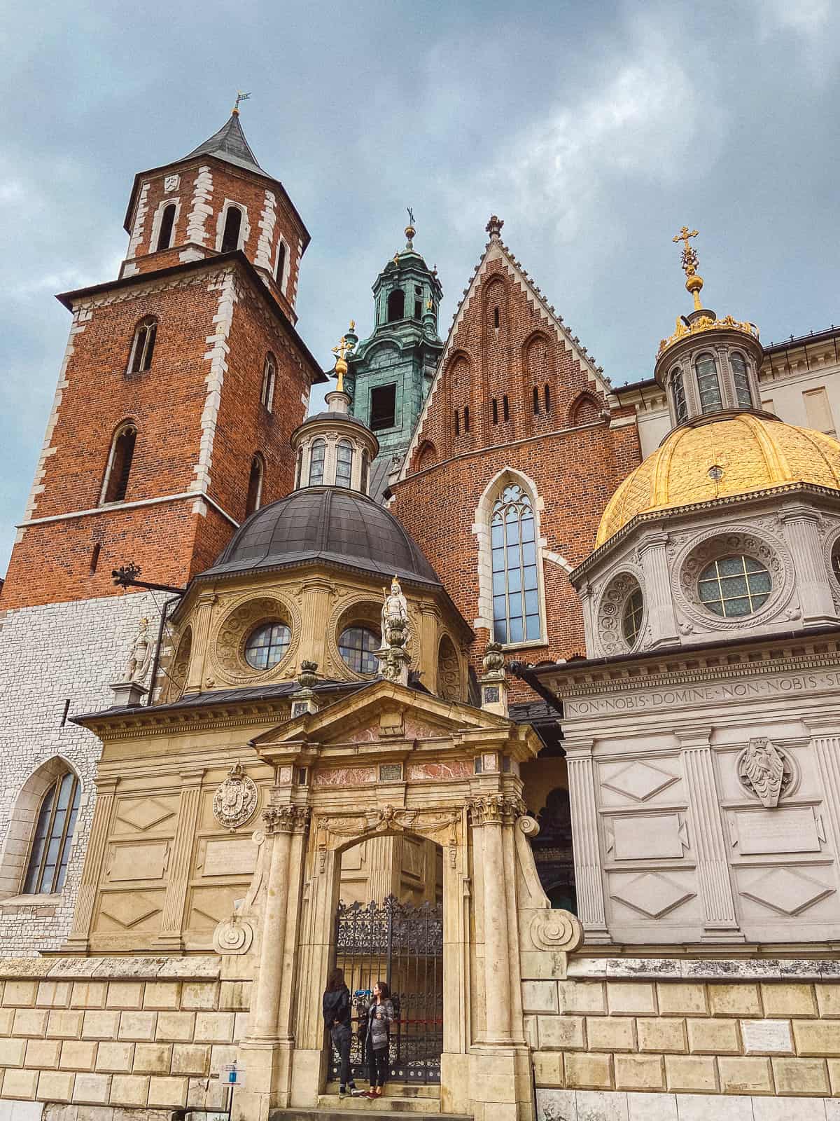 The historical and ornate architectural details of Wawel Cathedral in Krakow, featuring a mix of Gothic, Renaissance, and Baroque elements, under a cloudy sky conveying a sense of historical depth and cultural significance.