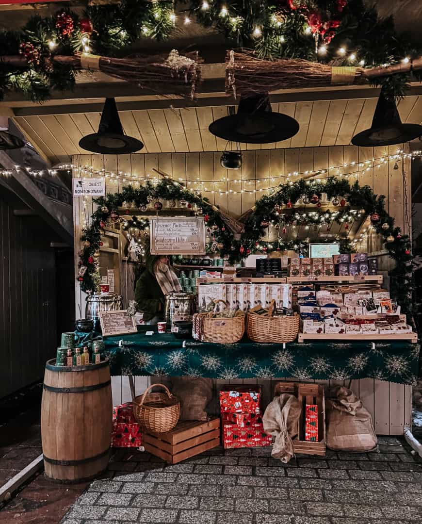 Cozy Christmas market stall adorned with garlands and lights, offering festive decorations and seasonal treats in Krakow