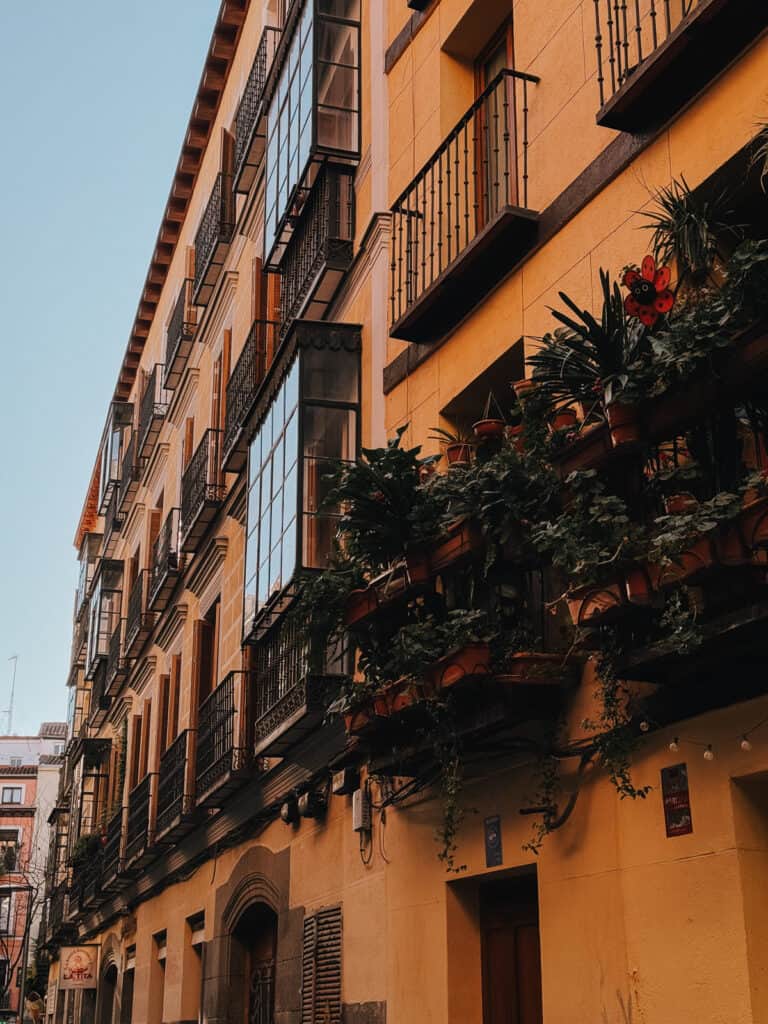 Traditional European architecture with rows of balconies filled with lush green plants, under a clear blue sky, showcasing urban residential beauty in a historic district.