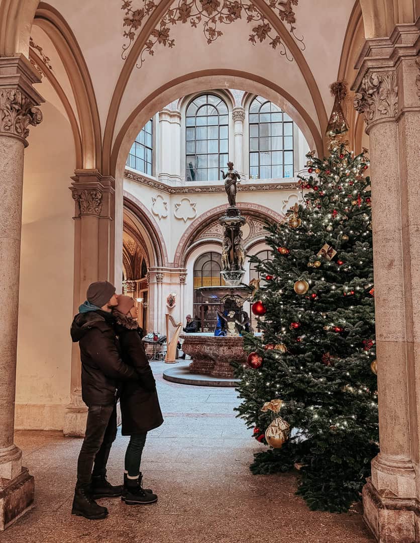 A couple stands in front of a beautifully lit Christmas tree in Vienna