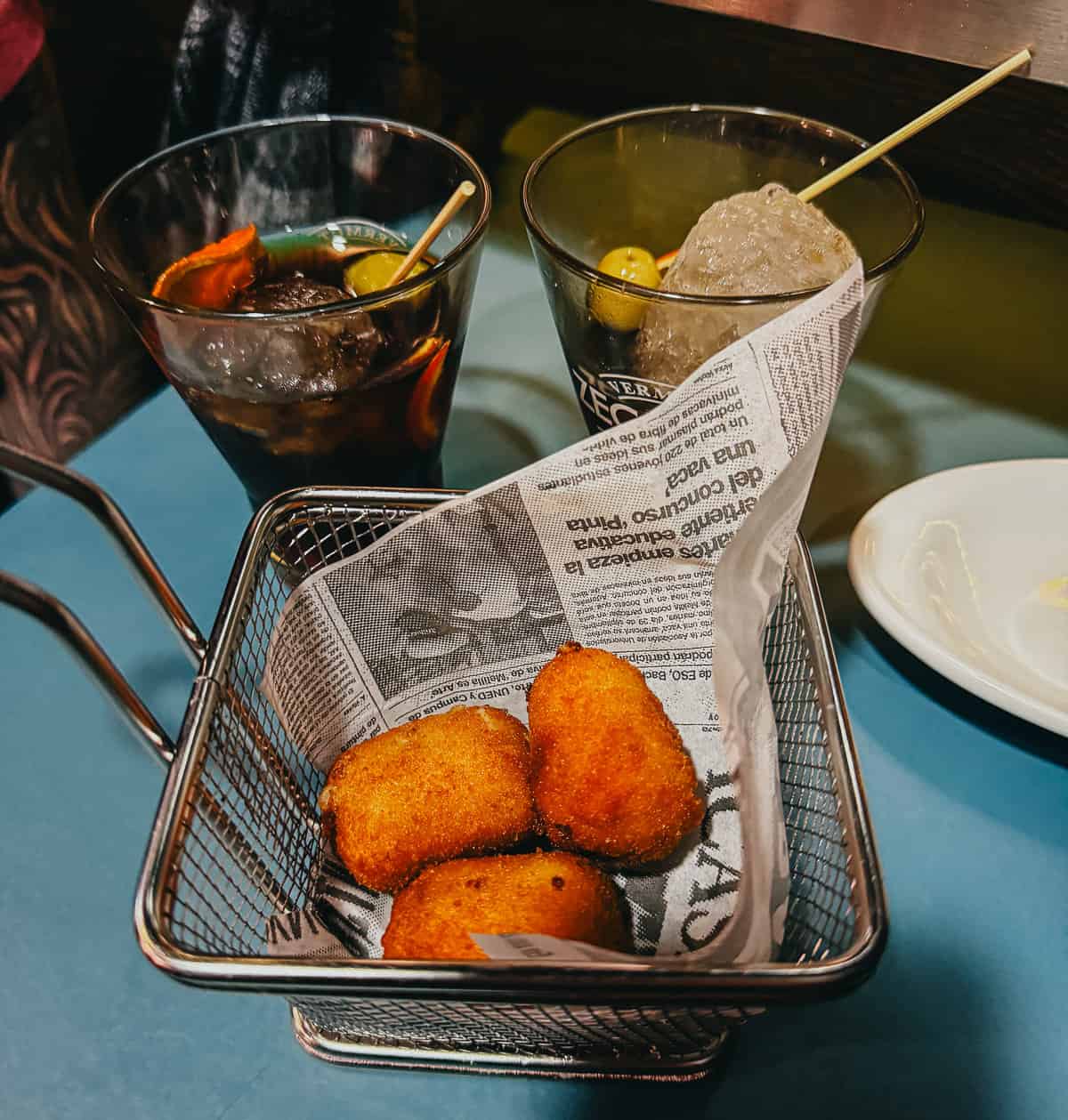 3 Spanish croquettes in a bowl with 2 glasses of vermouth