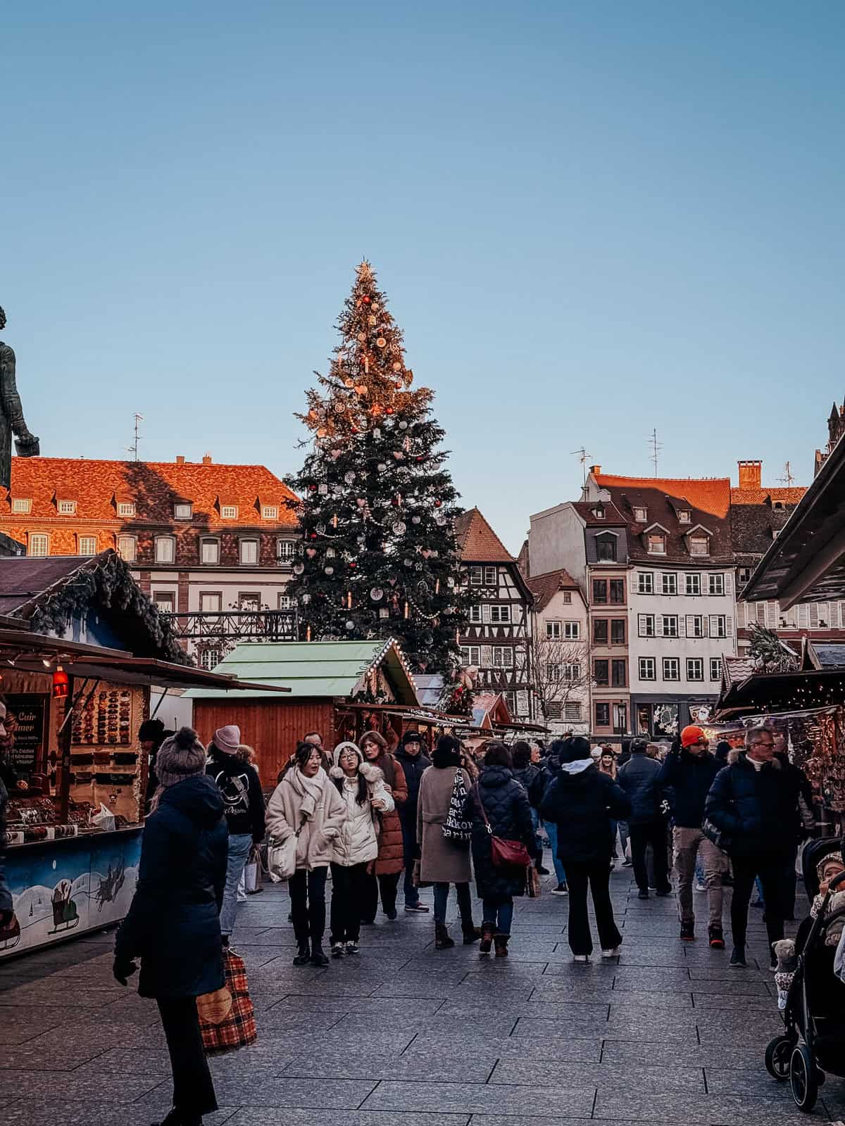 A bustling Christmas market in Strasbourg with a large christmas tree in the center