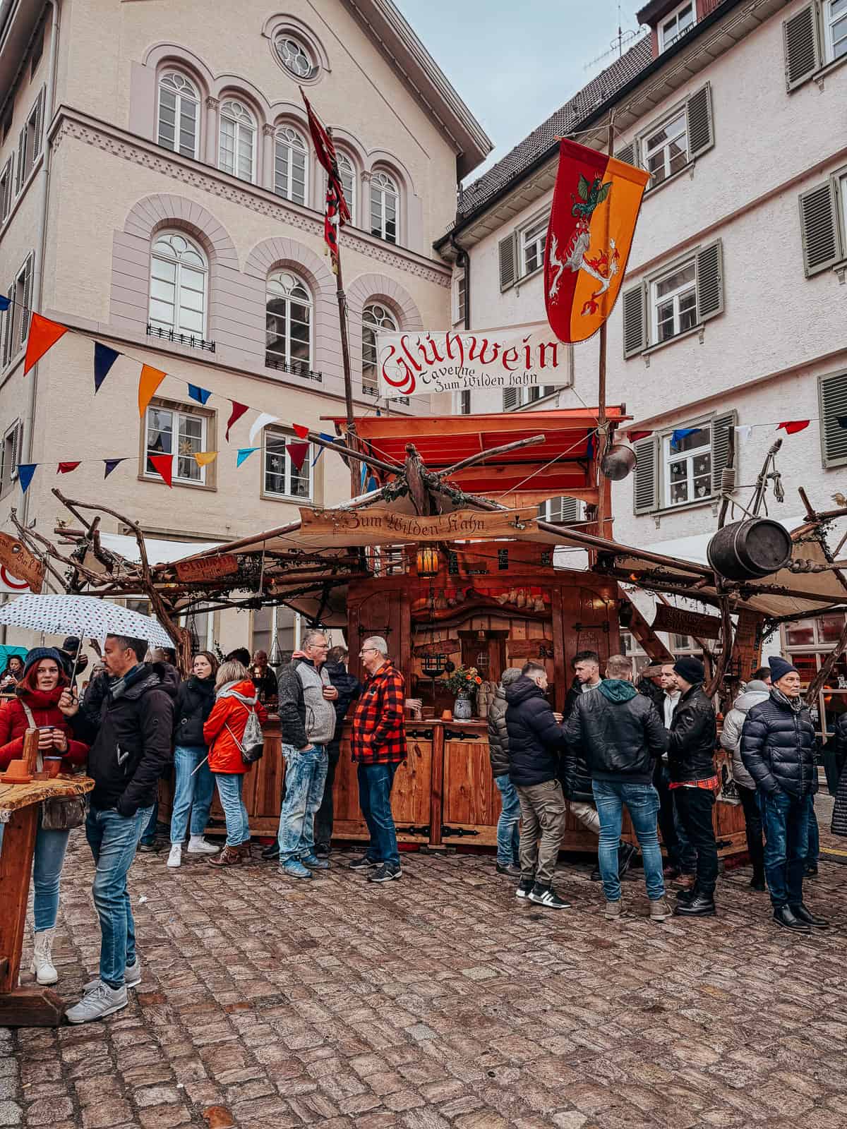 The first image captures a vibrant Glühwein (mulled wine) stand bustling with people. The colorful flags and medieval decorations create a festive atmosphere against the backdrop of traditional German architecture.