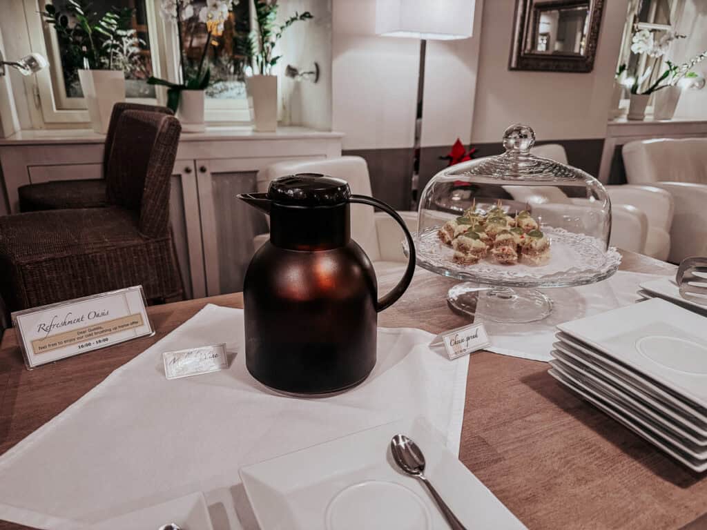 a black pot of mulled wine beside a tray of canapes on a table