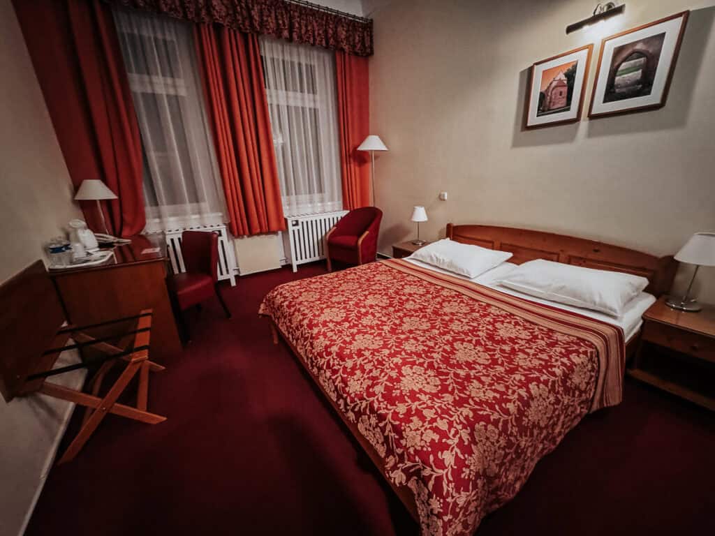 a vintage looking hotel room with red curtains and red and agold quilt