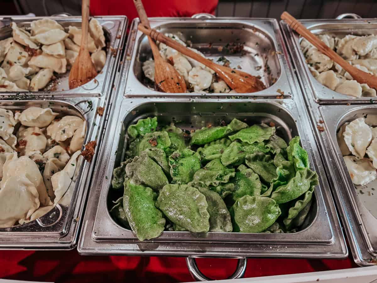 Close-up view of trays filled with traditional Polish pierogi, with plain and green spinach-flavored dough, served in a food stall at a Christmas market