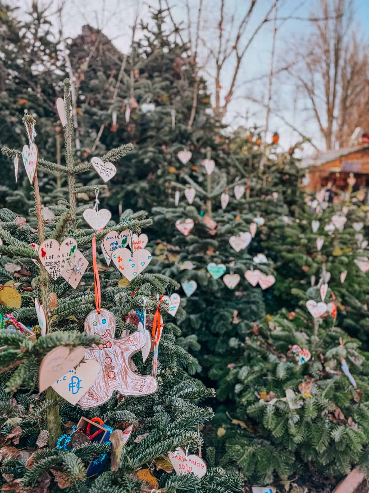 Multiple Christmas trees decorated with colorful heart-shaped ornaments and a gingerbread man, creating a festive and playful atmosphere.