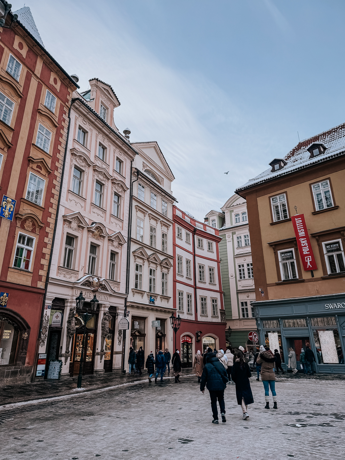 pastel buildings in Prague with icy streets as people walk 