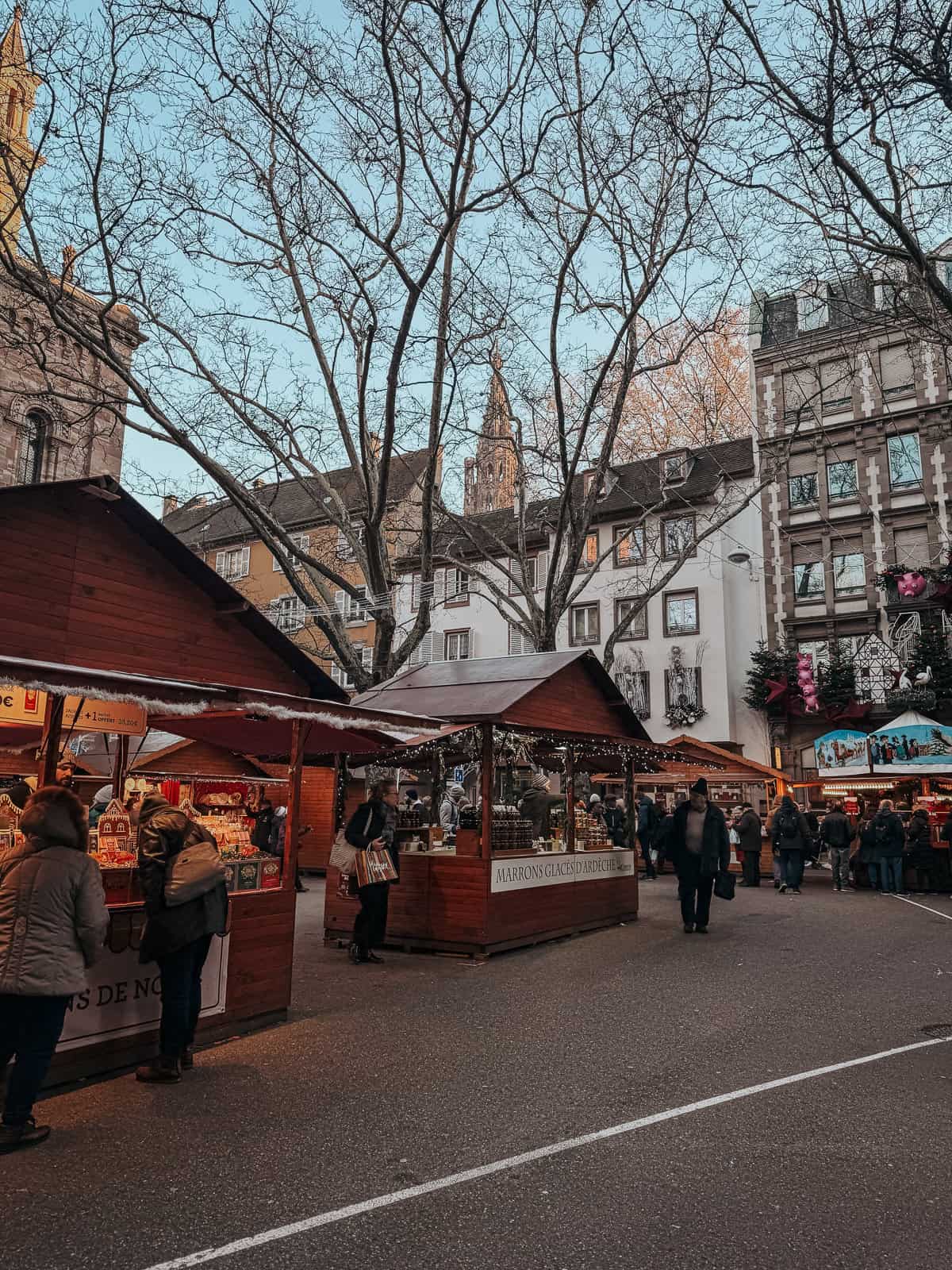 A vibrant Christmas market set in a square with the St. Thomas church in the background, featuring traditional stalls and a lively crowd