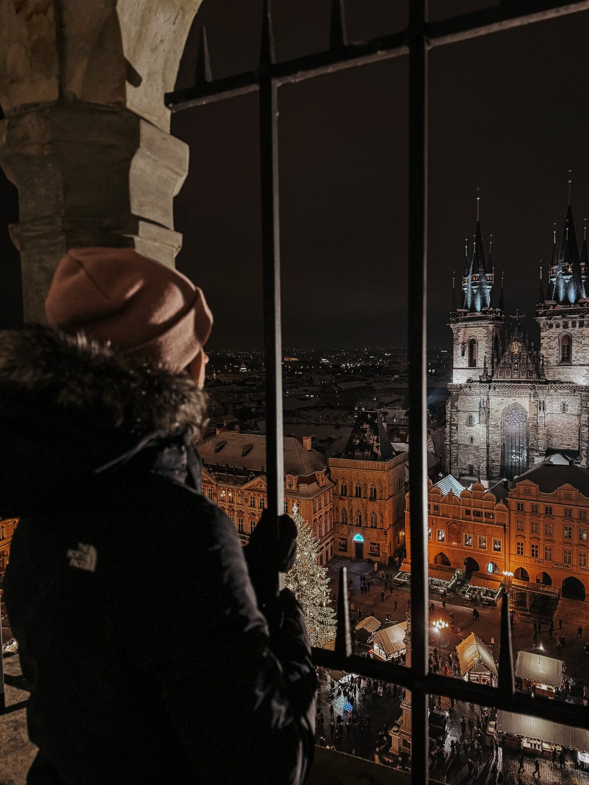 A woman overlooking the lit up Prague christmas market at night