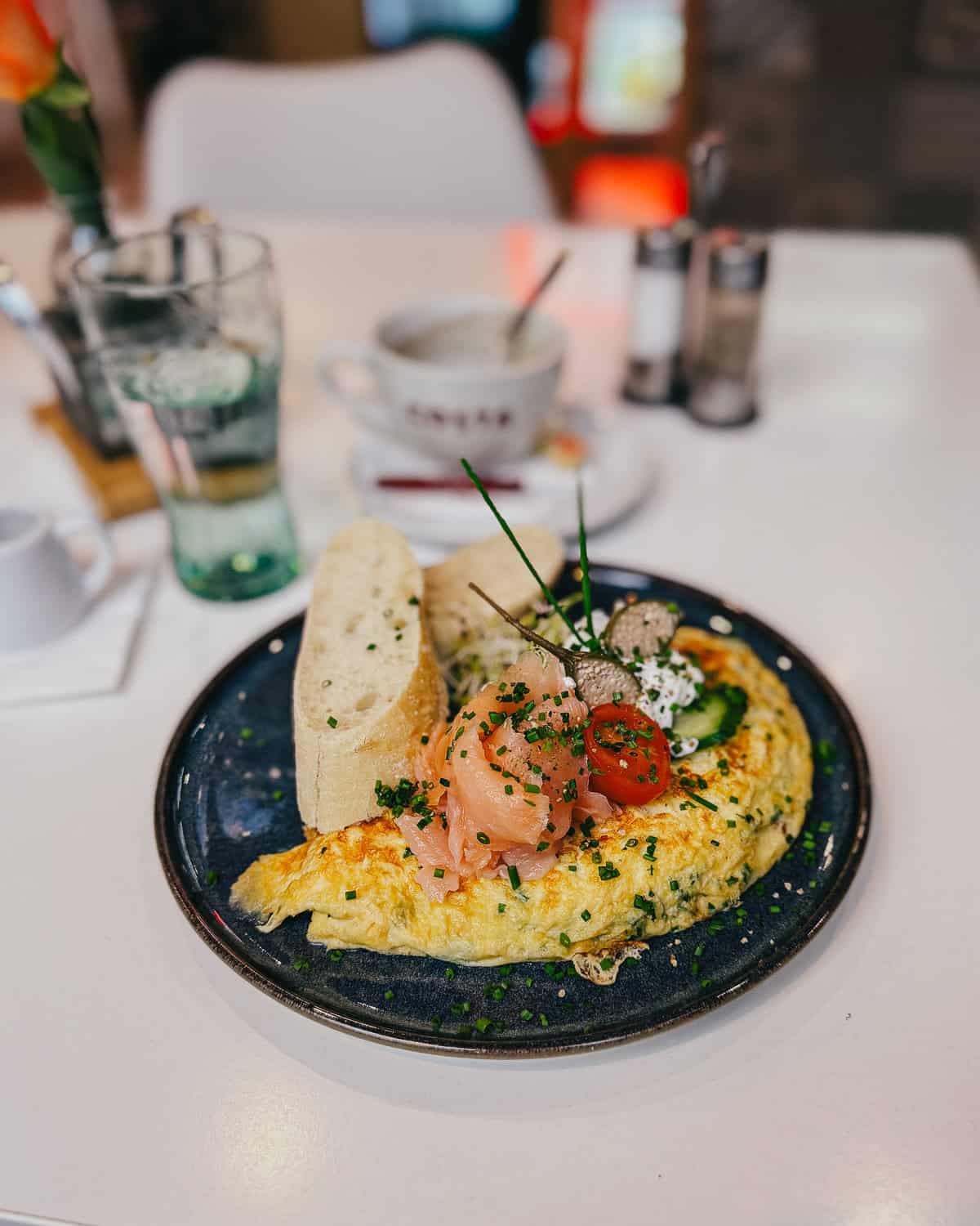 A fluffy omelete on blue plate with cucumber and smoked salmon on a simple, white table