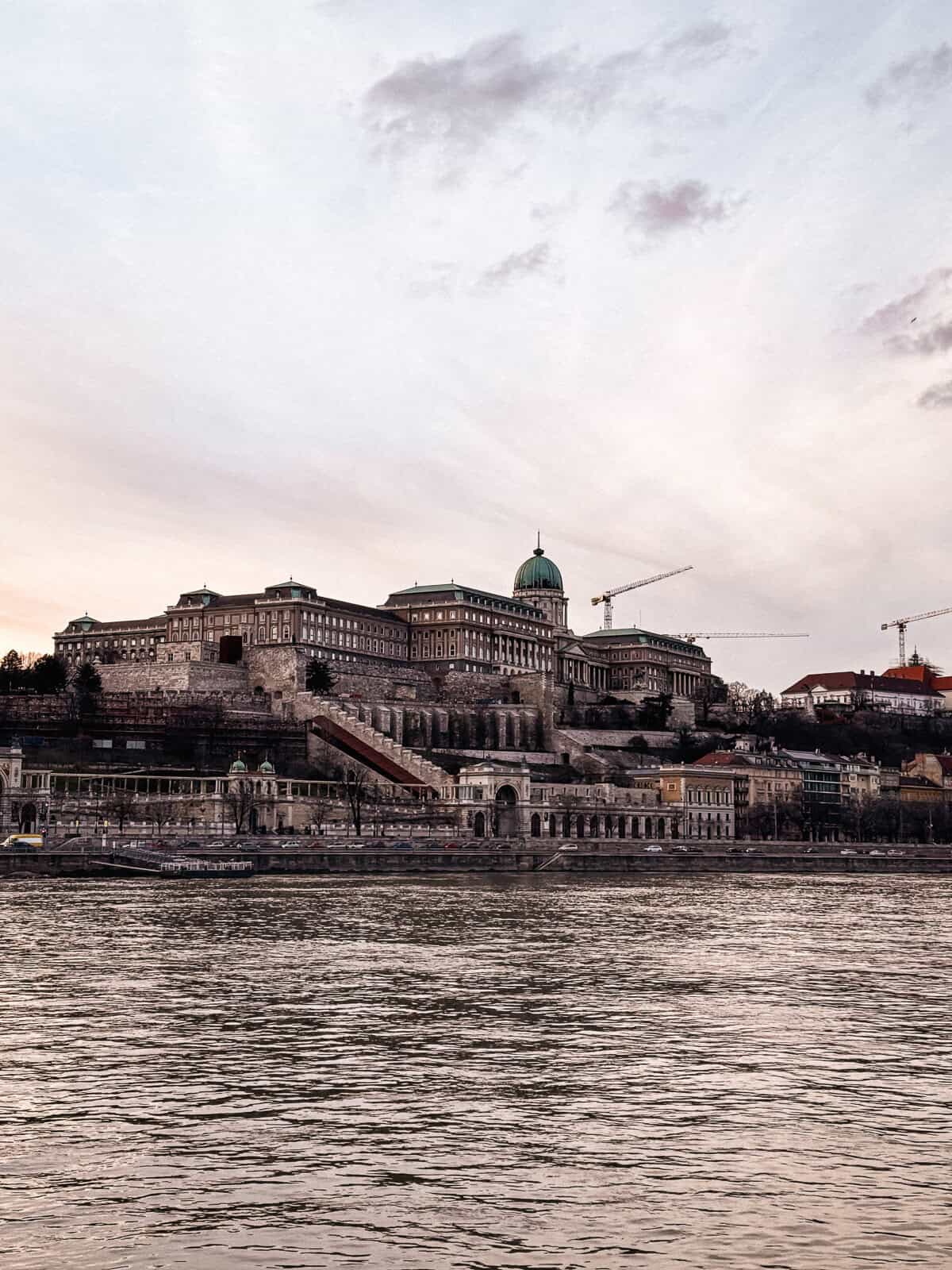 The buda castle on a high in Budapest at sunset with a bright pink sky