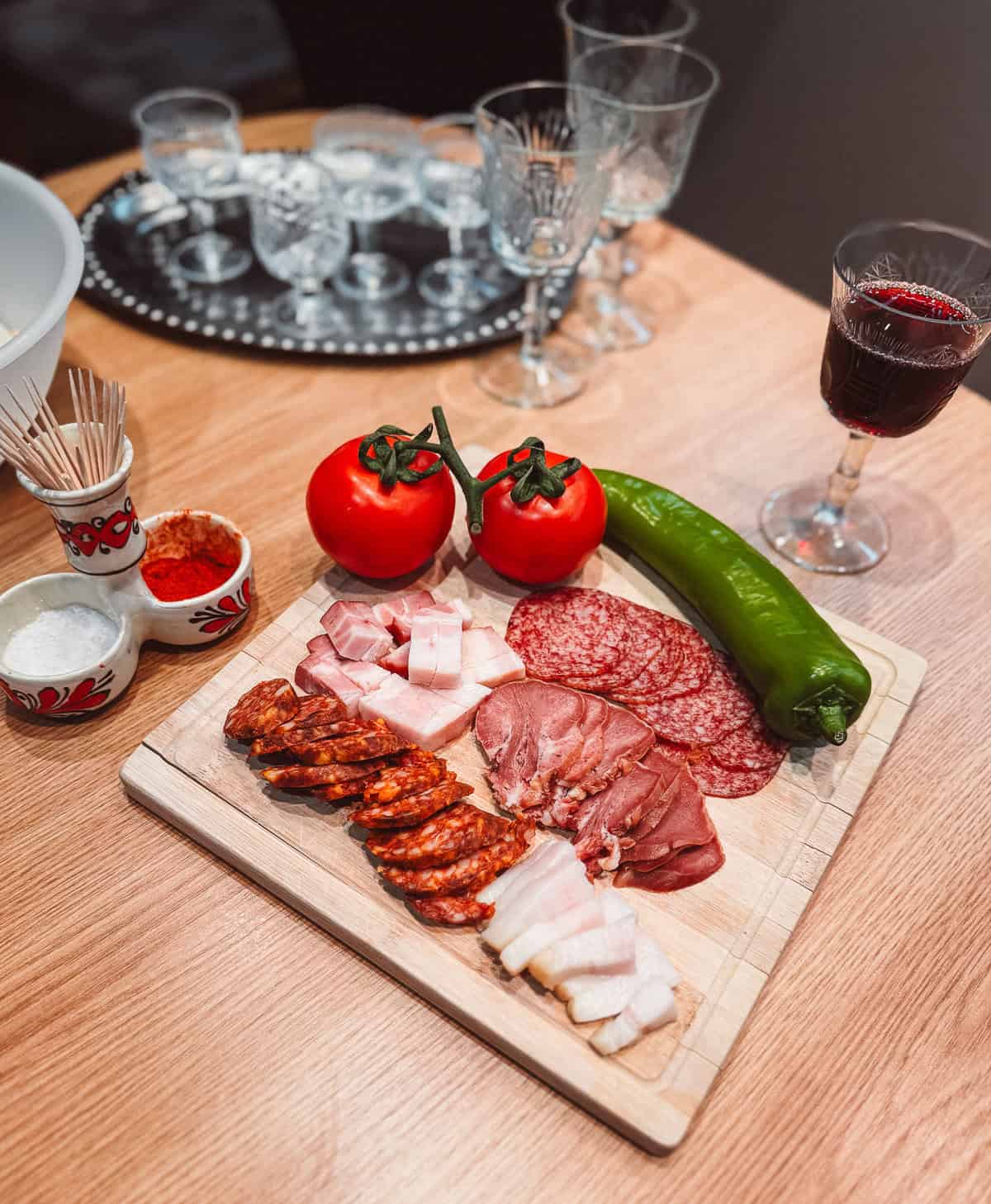 a tray with vegetables and Hungarian meat with wine glasses in the background