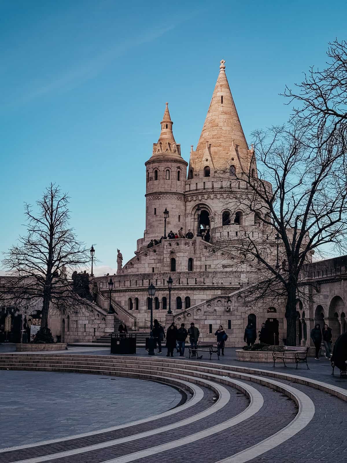 Fishermans Bastion in Budpest against a blue sky with a few dark shadows walking in front of it