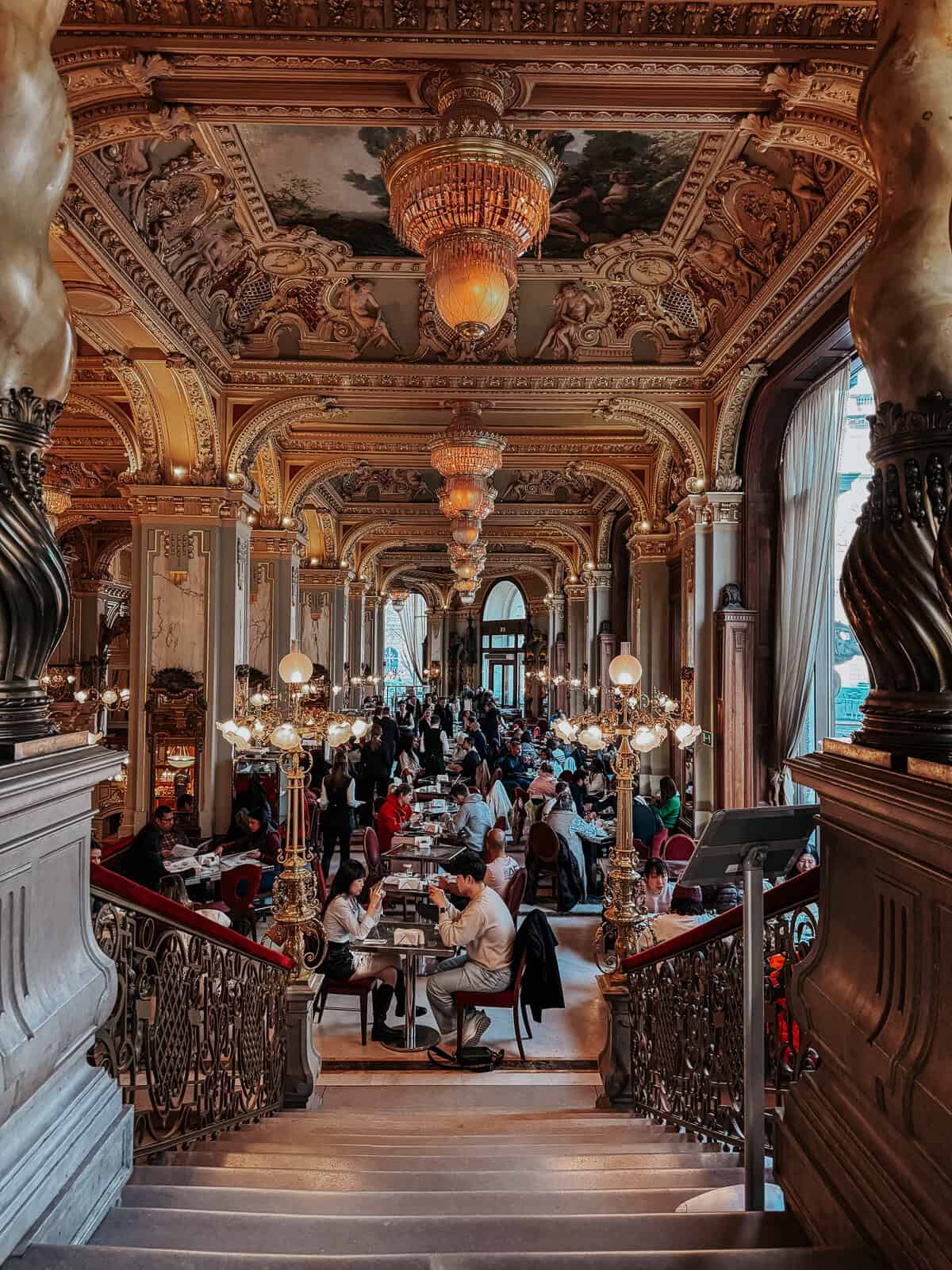 The famous new york cafe in Budapest with gold walls and people sitting down dining