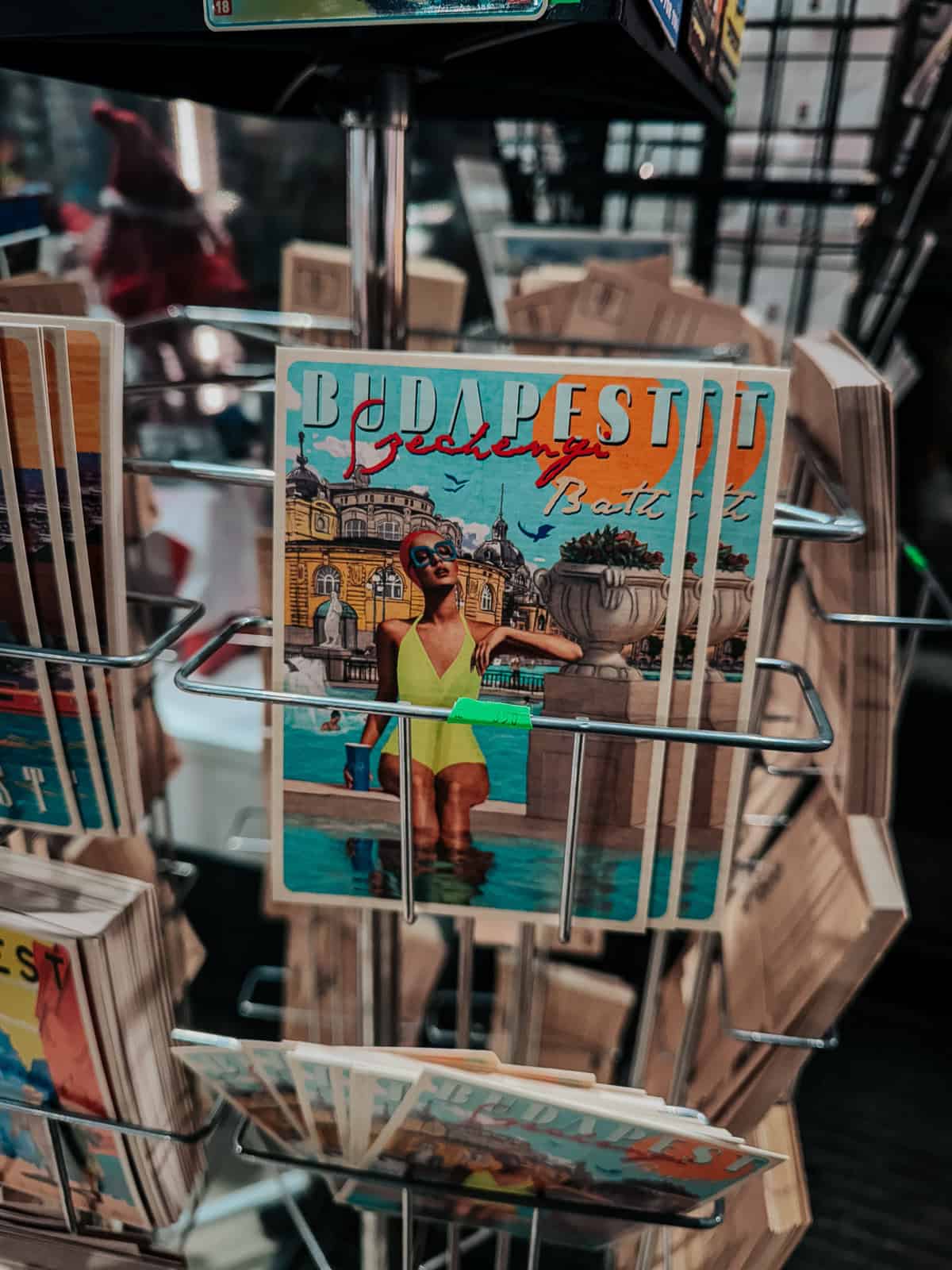 a blue postcard in a postcard carousel that has a woman in a yellow bathing suit