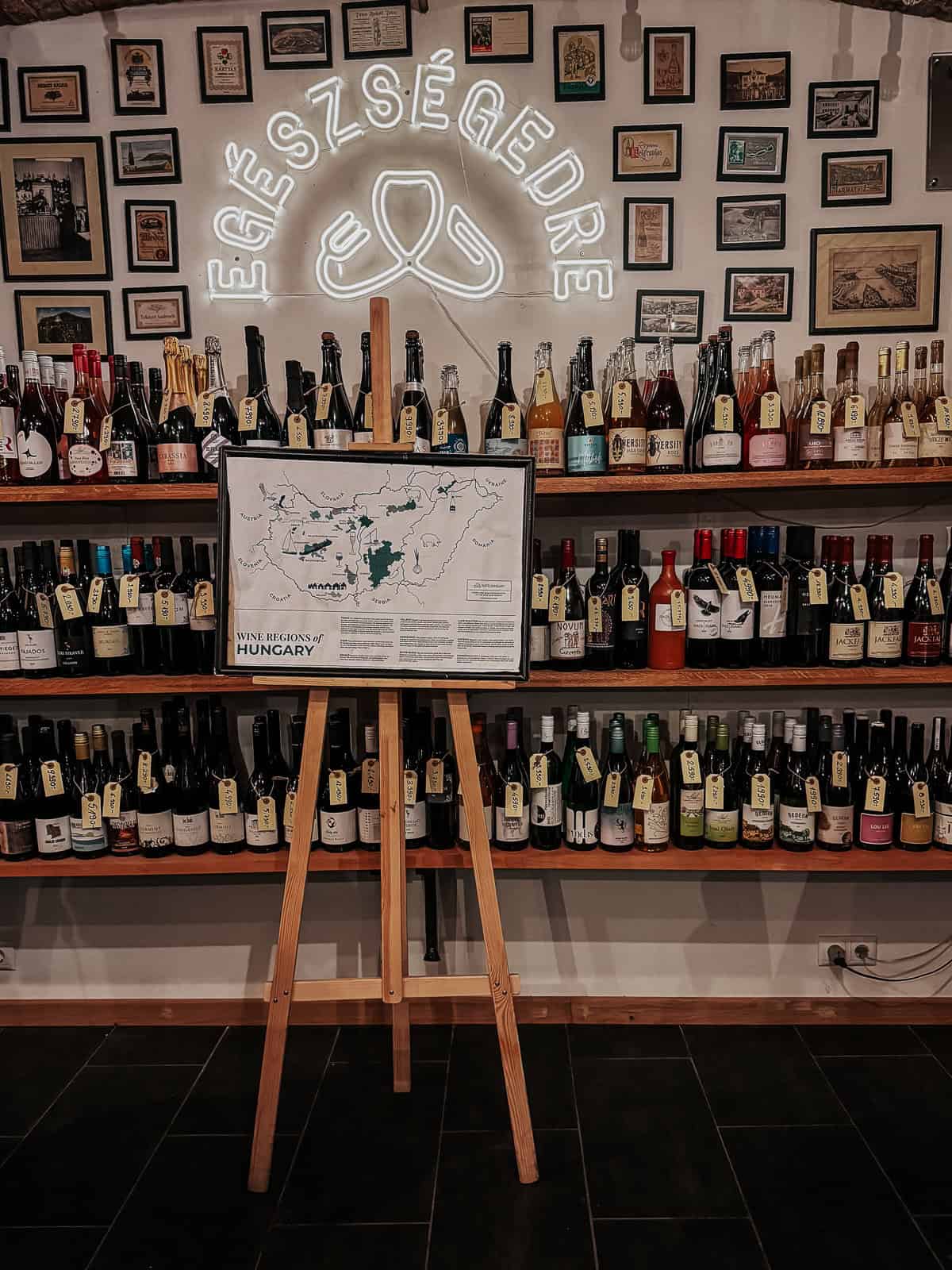 A wine shop interior with shelves full of various wine bottles. A neon sign with the word 