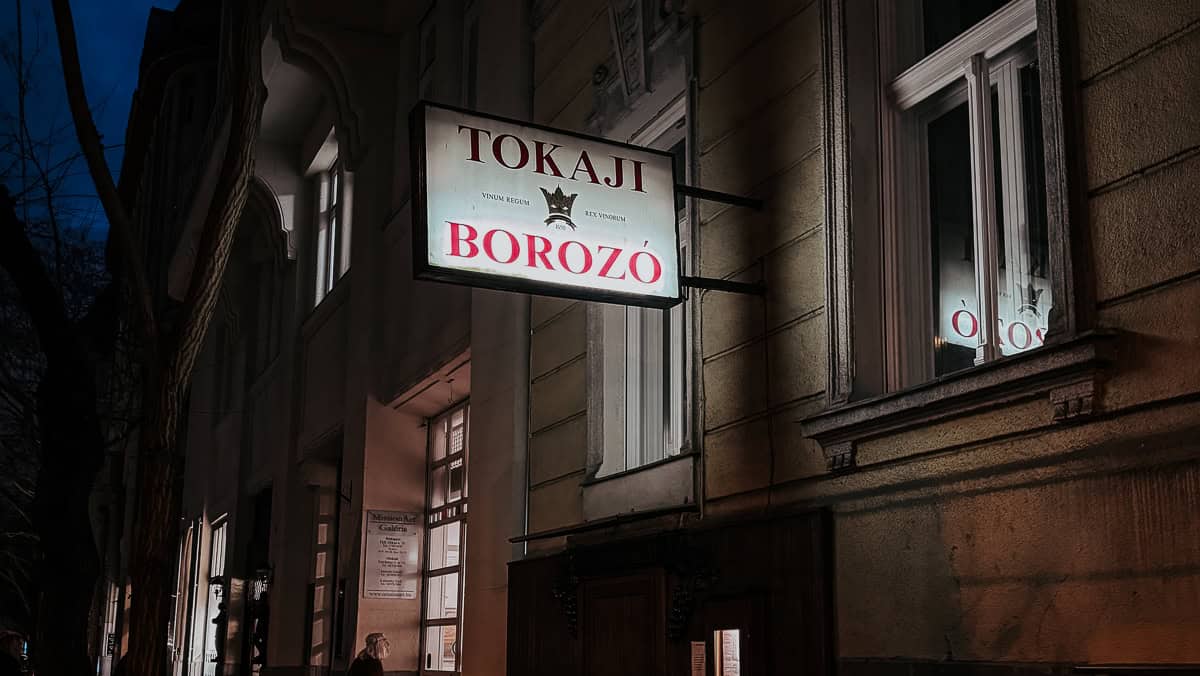 An exterior night view of a building with a lit sign reading 