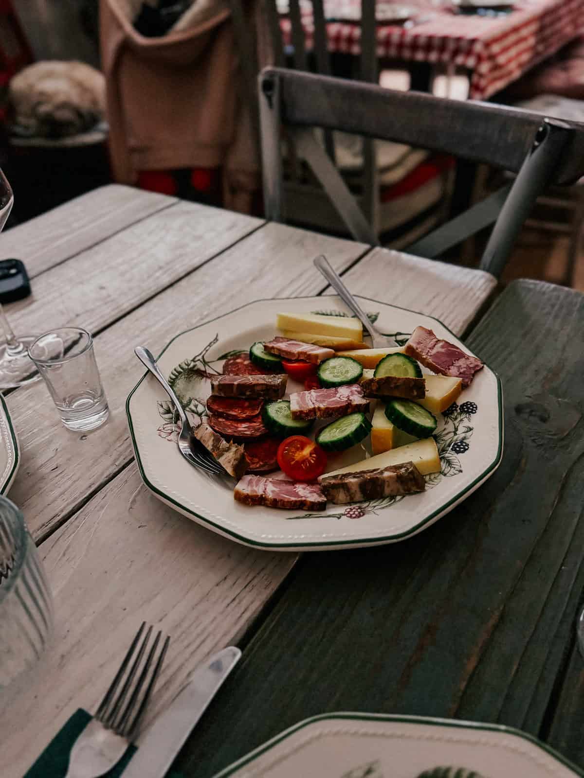 a beautiful plate of vegetables, cheese and meat on a white farm table