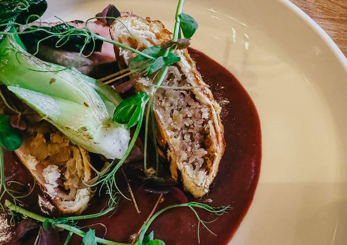 Close-up of the same dish showing the detailed texture of the seared meat and the accompanying sauce and garnish.