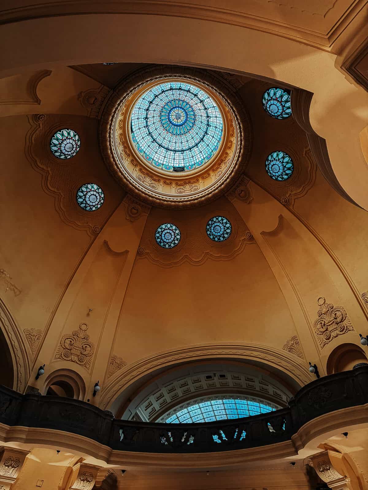 Interior view of the Gellért Thermal Bath dome, featuring intricate stained glass windows and ornate architectural details.