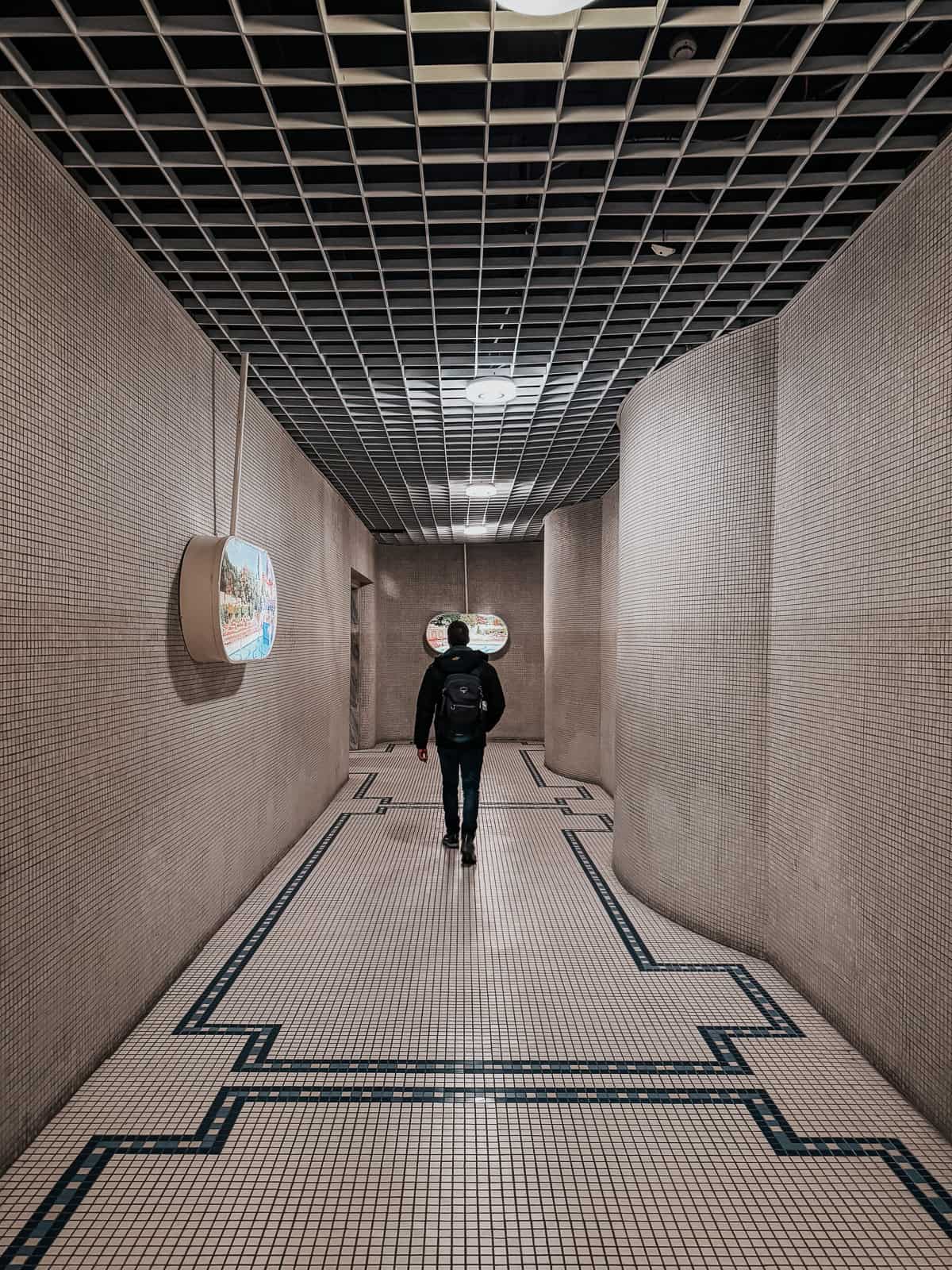 Corridor in the Gellért Thermal Bath, with a man walking towards the end under a tiled ceiling.