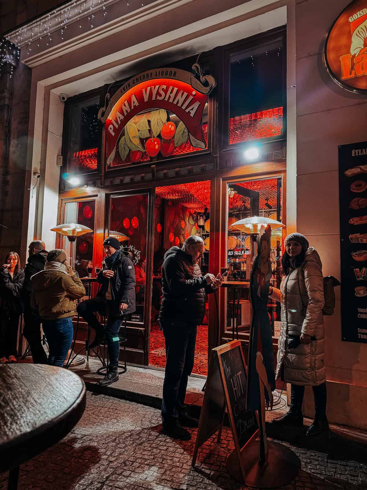 People standing around a lively red bar with a sign that says Piana Vyshnia